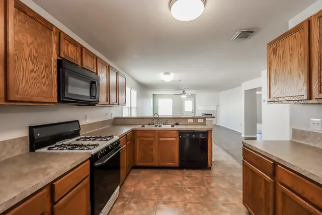 a kitchen with stainless steel appliances granite countertop a stove top oven a sink dishwasher and a refrigerator with wooden cabinets