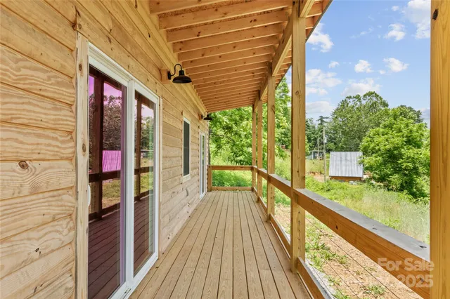 a view of a balcony with wooden floor and fence and a floor to ceiling window