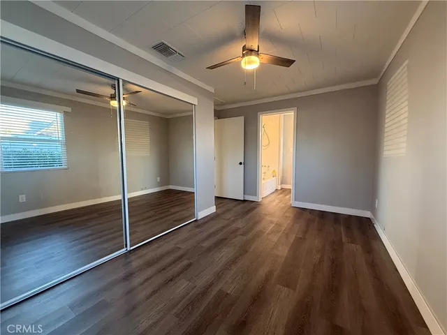 an empty room with wooden floor fan and window