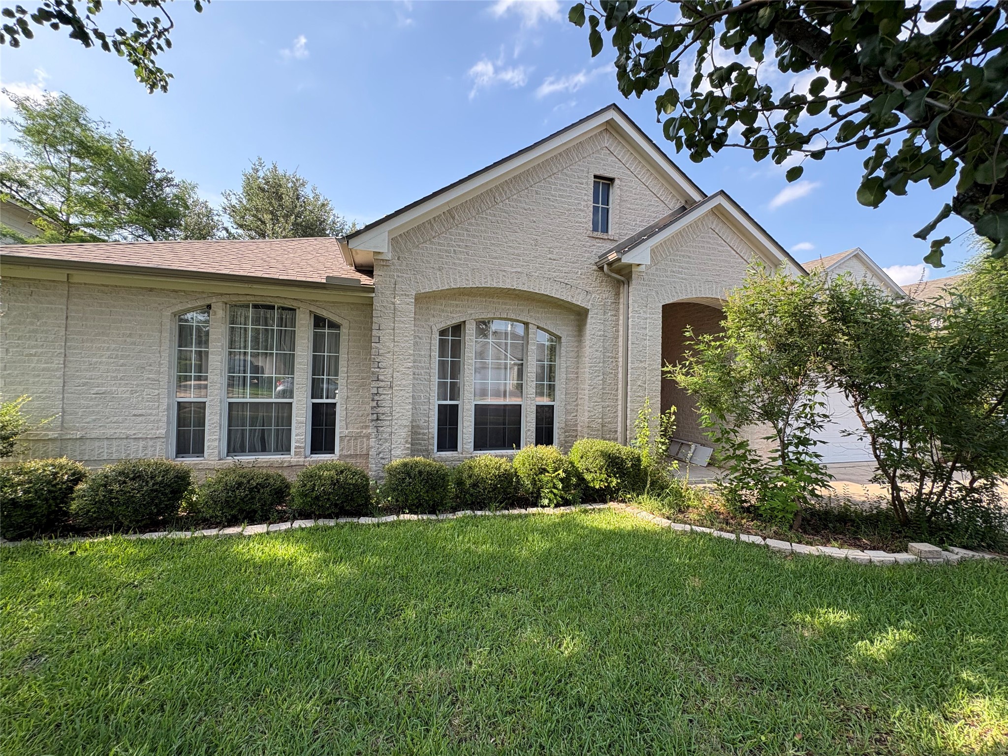 7006 Rambollet Terrace Round Rock, TX 78681 - Photo 3 of 38 A cream-colored brick facade welcomes guests, complemented by a neatly maintained lawn and verdant landscaping.