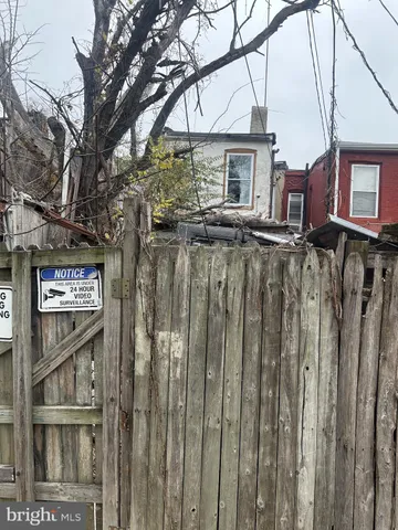 a view of a house with a wooden fence and large trees