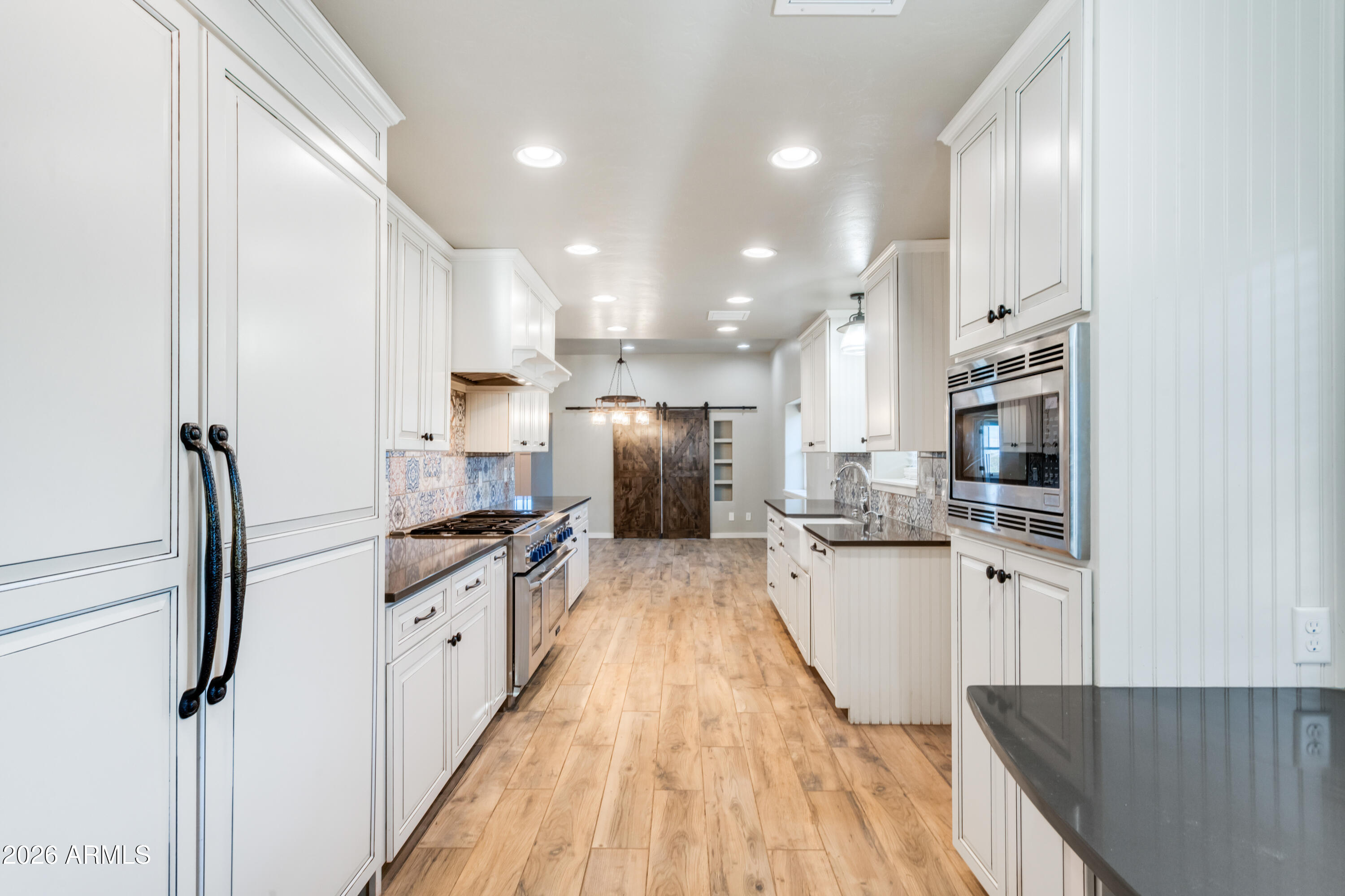 5306 East Spring Road Hereford, AZ 85615 - Photo 23 of 61 a kitchen with granite countertop a refrigerator oven a sink dishwasher and white cabinets with wooden floor