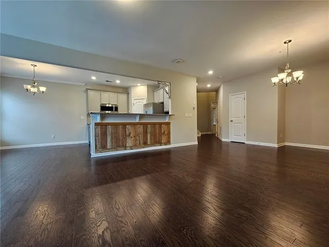 an empty room with wooden floor and a kitchen