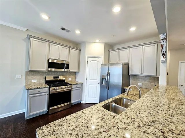 a kitchen with stainless steel appliances granite countertop a sink stove refrigerator and cabinets