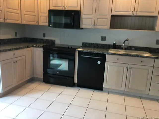 a kitchen with granite countertop white cabinets and stainless steel appliances