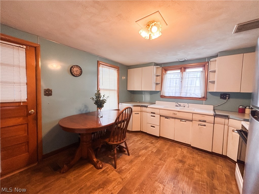 724 East Main Street Barnesville, OH 43713 - Photo 10 of 28 Kitchen featuring open shelves, light countertops, light wood finished floors, a textured ceiling, and freestanding refrigerator