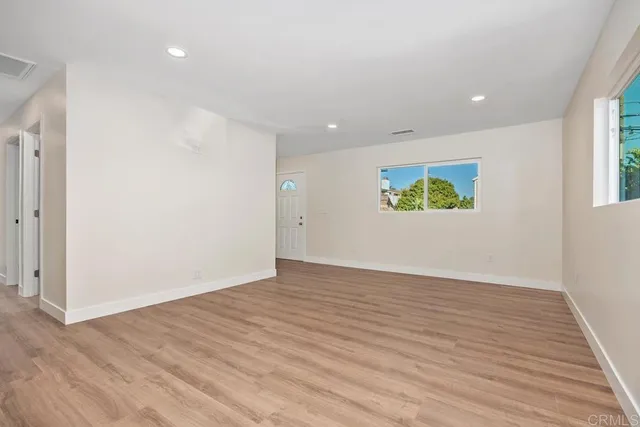 a view of an empty room with window and wooden floor
