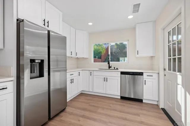 a kitchen with white cabinets and refrigerator