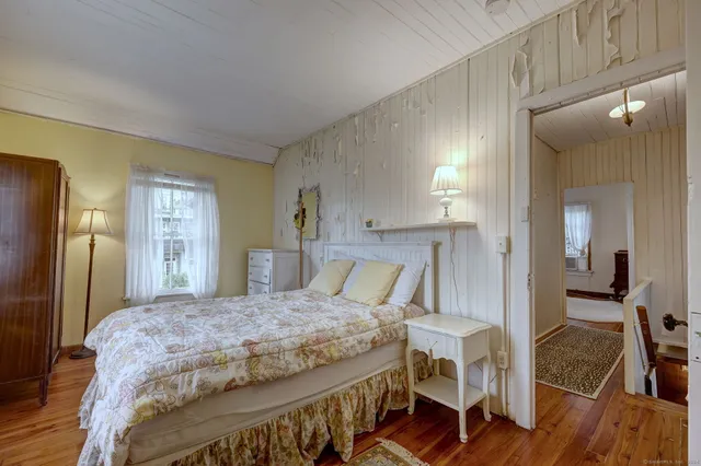 a bedroom with a bed a table and painting on the wall