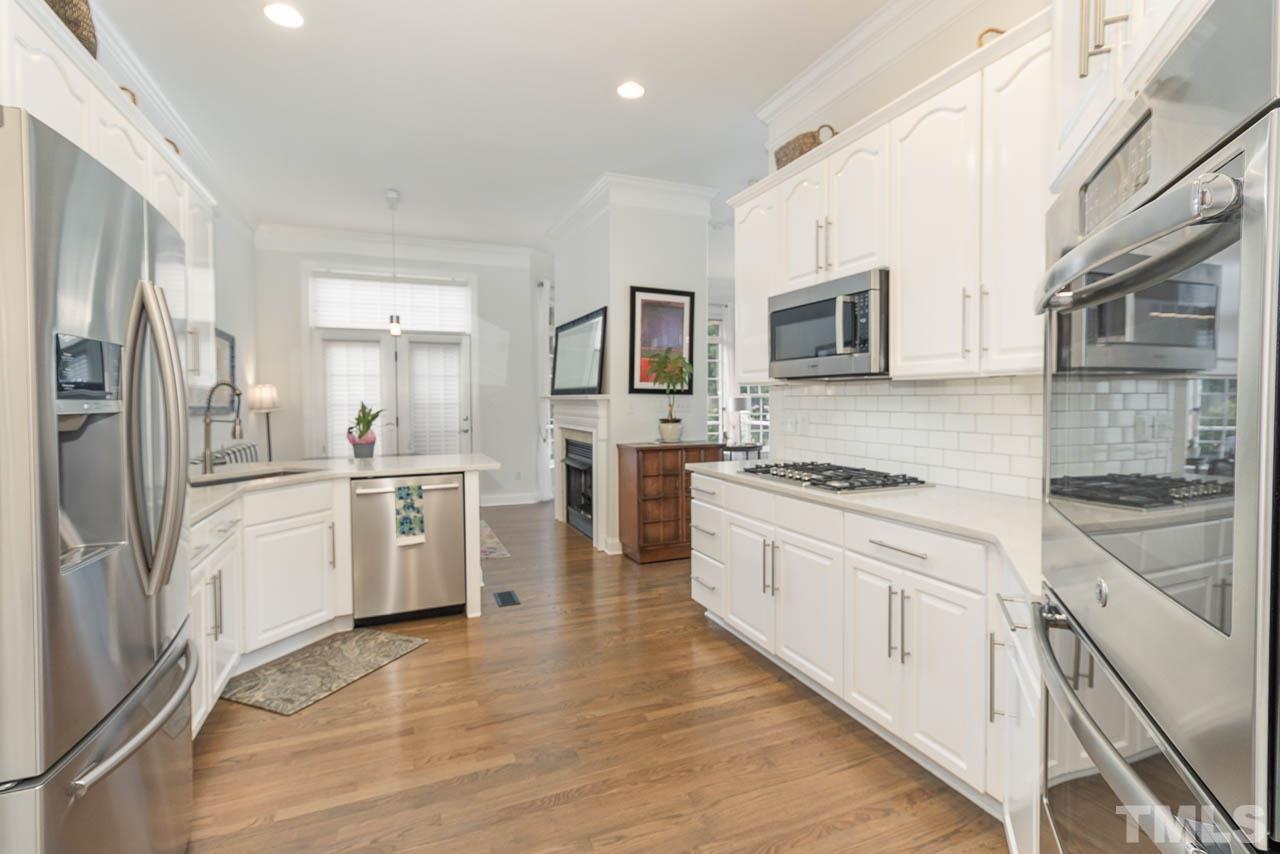 12507 Megan Hill Court Raleigh, NC 27614 - Photo 12 of 39 a large kitchen with stainless steel appliances granite countertop a stove top oven a refrigerator a sink and dishwasher with wooden floor