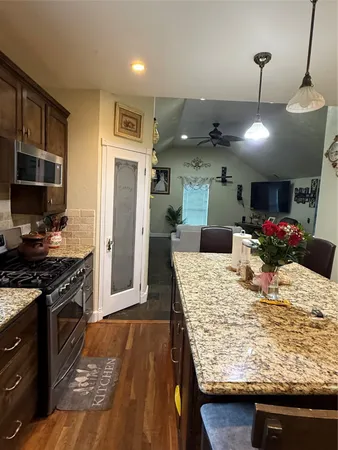 a kitchen with stainless steel appliances kitchen island granite countertop wooden cabinets and granite counter tops