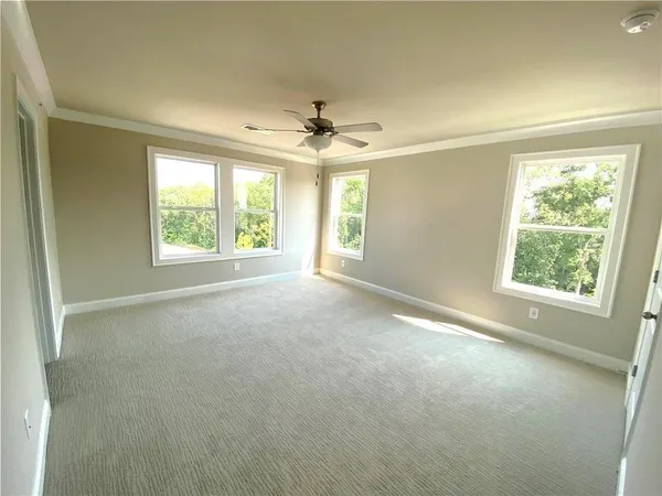 an empty room with windows and chandelier fan