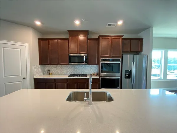 a kitchen with stainless steel appliances kitchen island granite countertop a refrigerator and a stove top oven