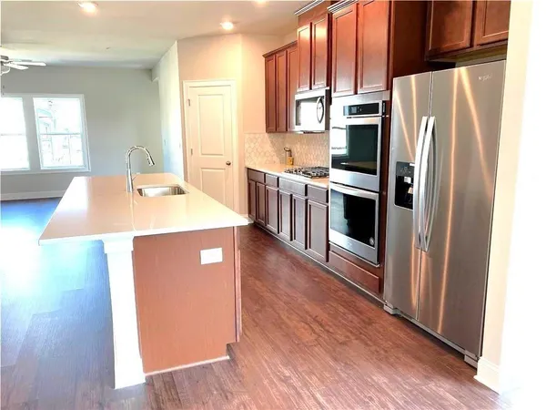 a kitchen with stainless steel appliances a refrigerator a stove a sink cabinets and wooden floor