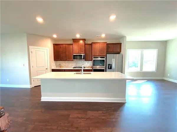 a view of kitchen with kitchen island a sink wooden floor and a counter top space
