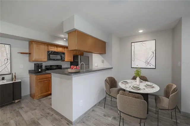 a kitchen with stainless steel appliances granite countertop a sink a stove a microwave a dining table and chairs