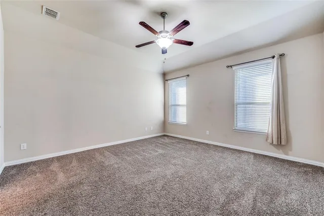 an empty room with ceiling fan and window