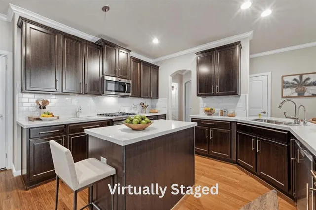 a kitchen with kitchen island granite countertop a sink appliances cabinets and wooden floor