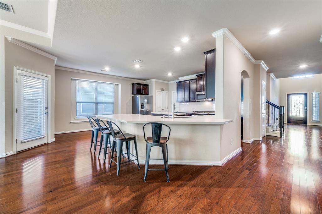 16008 Aquilla Way Prosper, TX 75078 - Photo 9 of 33 a open kitchen with stainless steel appliances granite countertop a stove a refrigerator a microwave a dining table and chairs with wooden floor