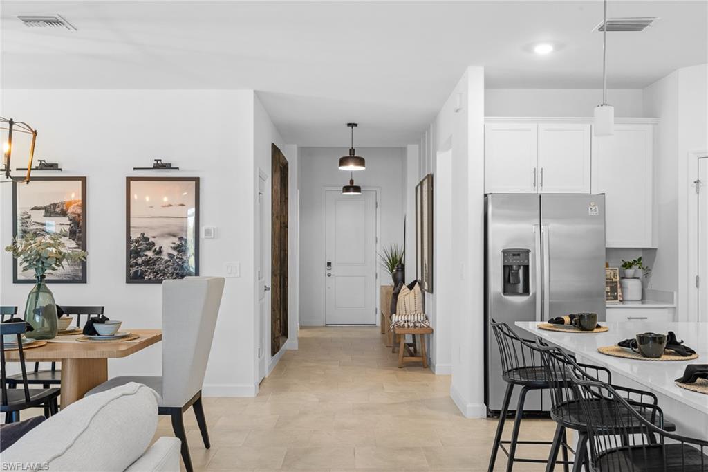 17752 Saddleback Loop North Fort Myers, FL 33917 - Photo 12 of 37 Kitchen with stainless steel fridge, white cabinets, light countertops, and decorative light fixtures