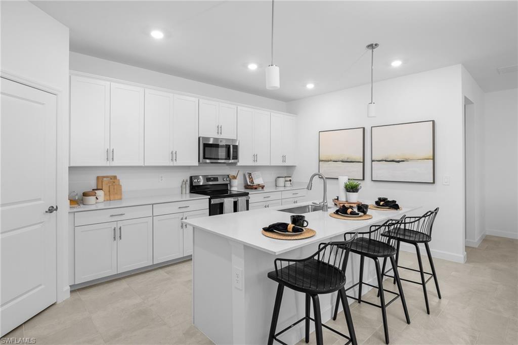 17752 Saddleback Loop North Fort Myers, FL 33917 - Photo 17 of 37 Kitchen featuring stainless steel appliances, light countertops, a kitchen breakfast bar, white cabinetry, and pendant lighting