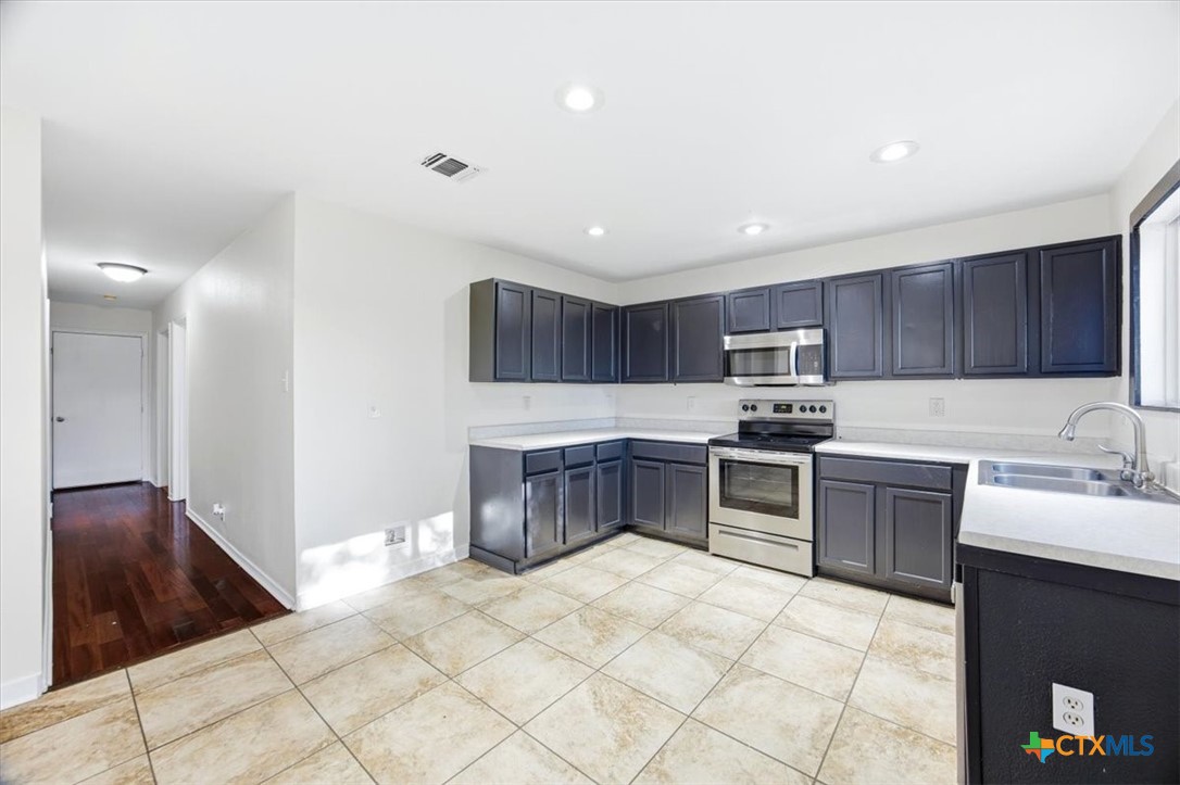 2030 Castleberry Ridge New Braunfels, TX 78130 - Photo 18 of 43 a kitchen with stainless steel appliances granite countertop a stove a sink and a refrigerator