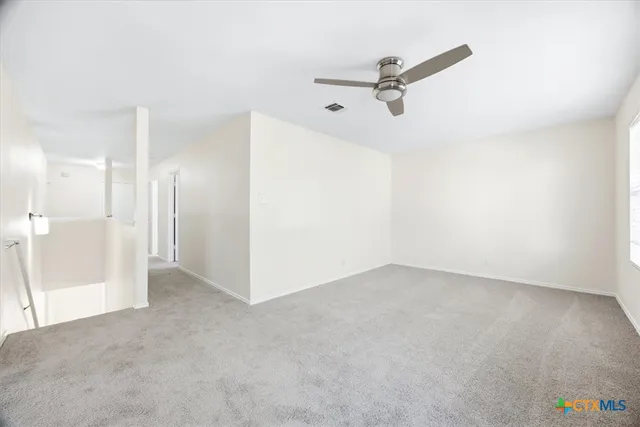 a view of a livingroom with a ceiling fan and refrigerator