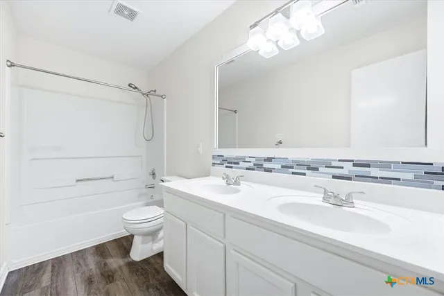 a bathroom with a sink a toilet a mirror and shower