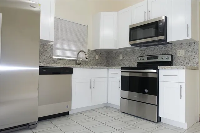 a kitchen with white cabinets and stainless steel appliances