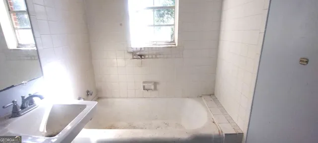 a bathroom with a tub a sink and a window