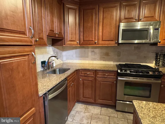 a kitchen with stainless steel appliances granite countertop a sink stove and microwave
