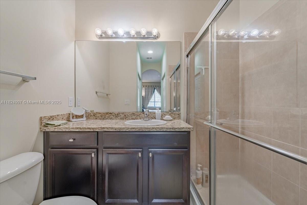 370 Lake Monterey Circle Boynton Beach, FL 33426 - Photo 17 of 17 a bathroom with a granite countertop sink a toilet and with a mirror