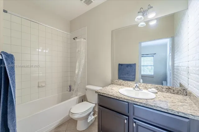 a bathroom with a granite countertop sink a toilet a mirror and shower
