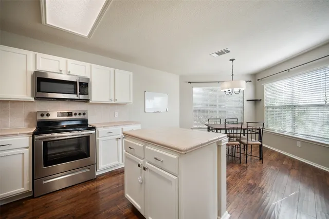 a kitchen with a stove top oven a sink dishwasher a dining table and chairs with wooden floor