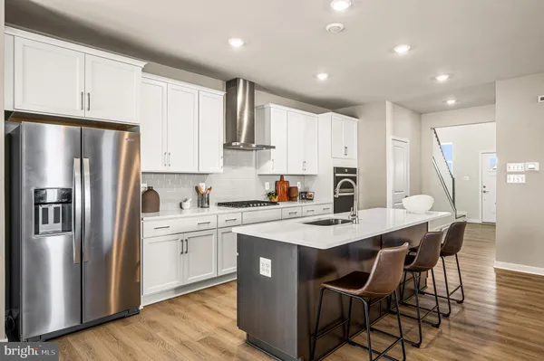 a kitchen with stainless steel appliances granite countertop a refrigerator a stove a sink a dining table and chairs