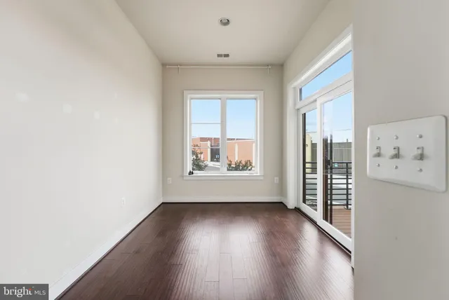 a view of an empty room with a window and wooden floor