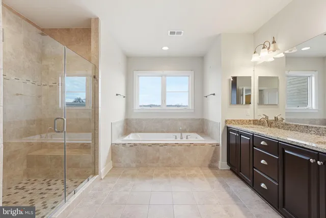 a spacious bathroom with a tub sink shower and mirror