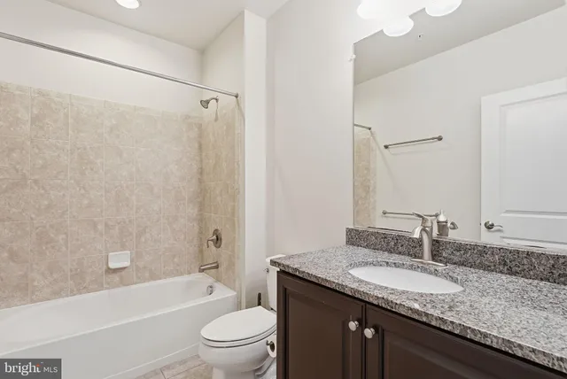 a bathroom with a granite countertop sink a toilet and shower