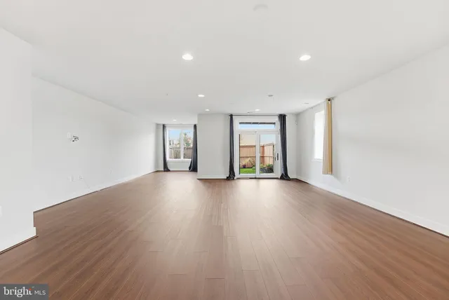 a view of an empty room with window and wooden floor