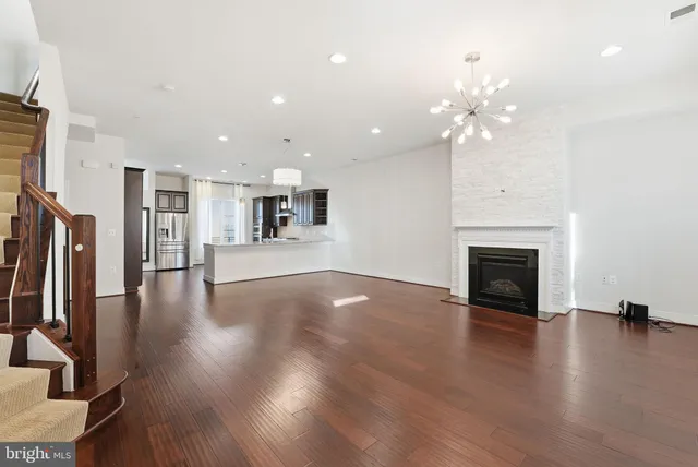 a view of a livingroom with a fireplace a chandelier and wooden floor