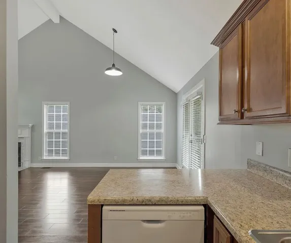 a kitchen with granite countertop a sink and dishwasher a stove top oven with wooden floor