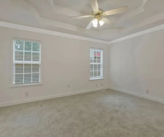 an empty room with chandelier fan and windows