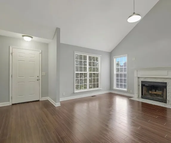 an empty room with wooden floor fireplace and windows