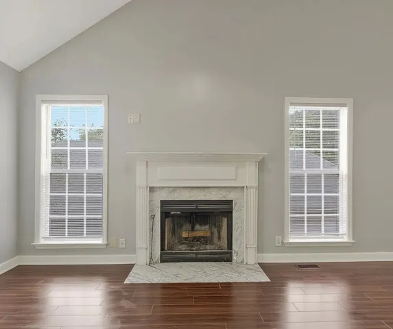 an empty room with wooden floor a fireplace and windows