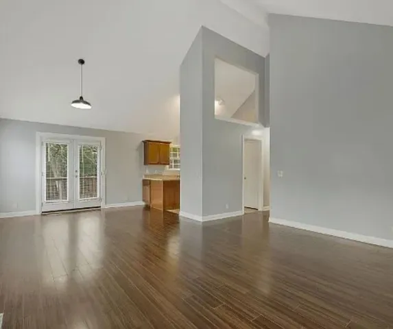 an empty room with wooden floor cabinet and windows