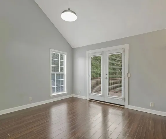 an empty room with wooden floor and windows