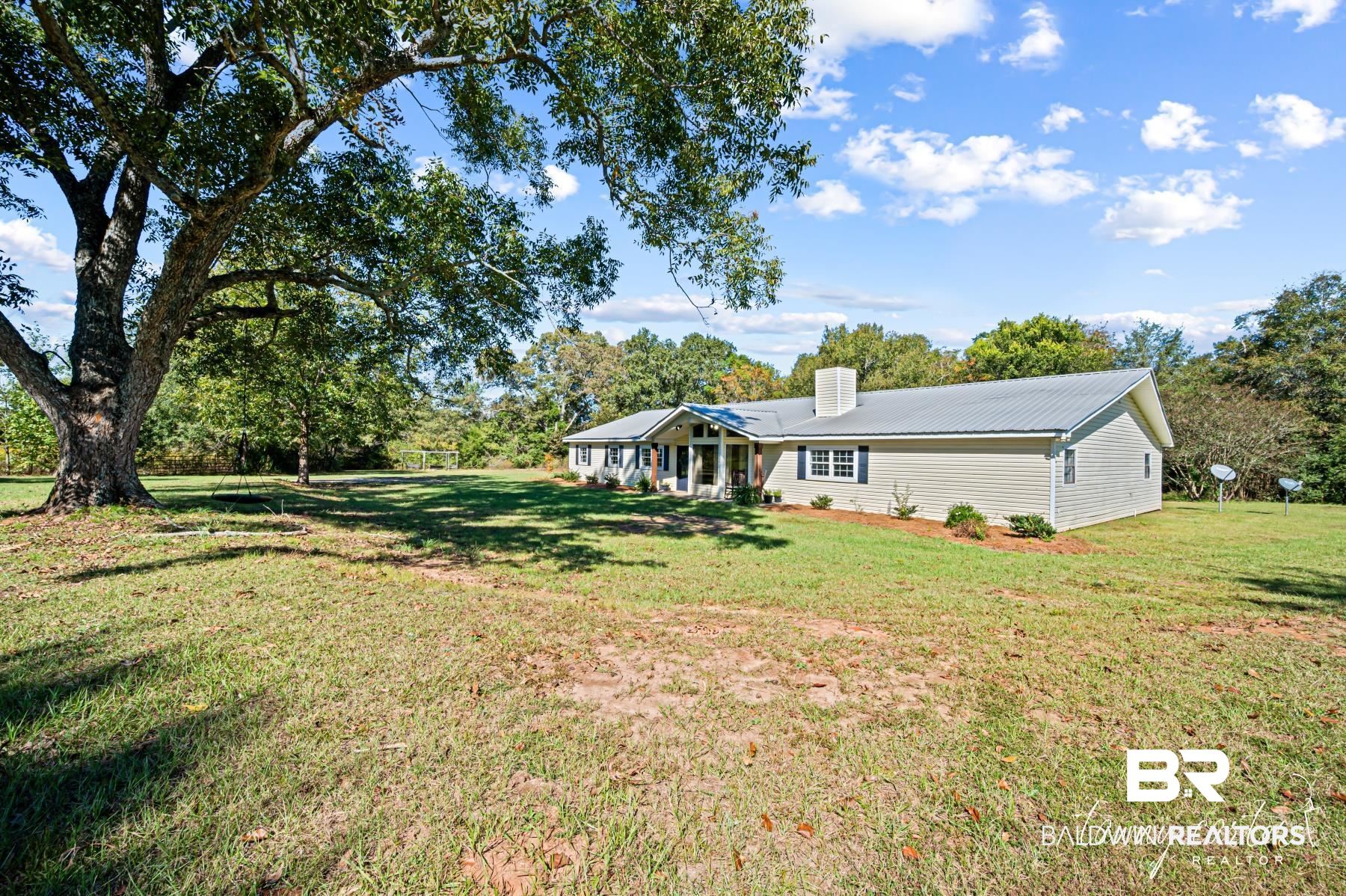 3086 Wild Fork Road Frisco City, AL 36445 - Photo 25 of 30 Back of property featuring a metal roof, a lawn, a chimney, and a patio area