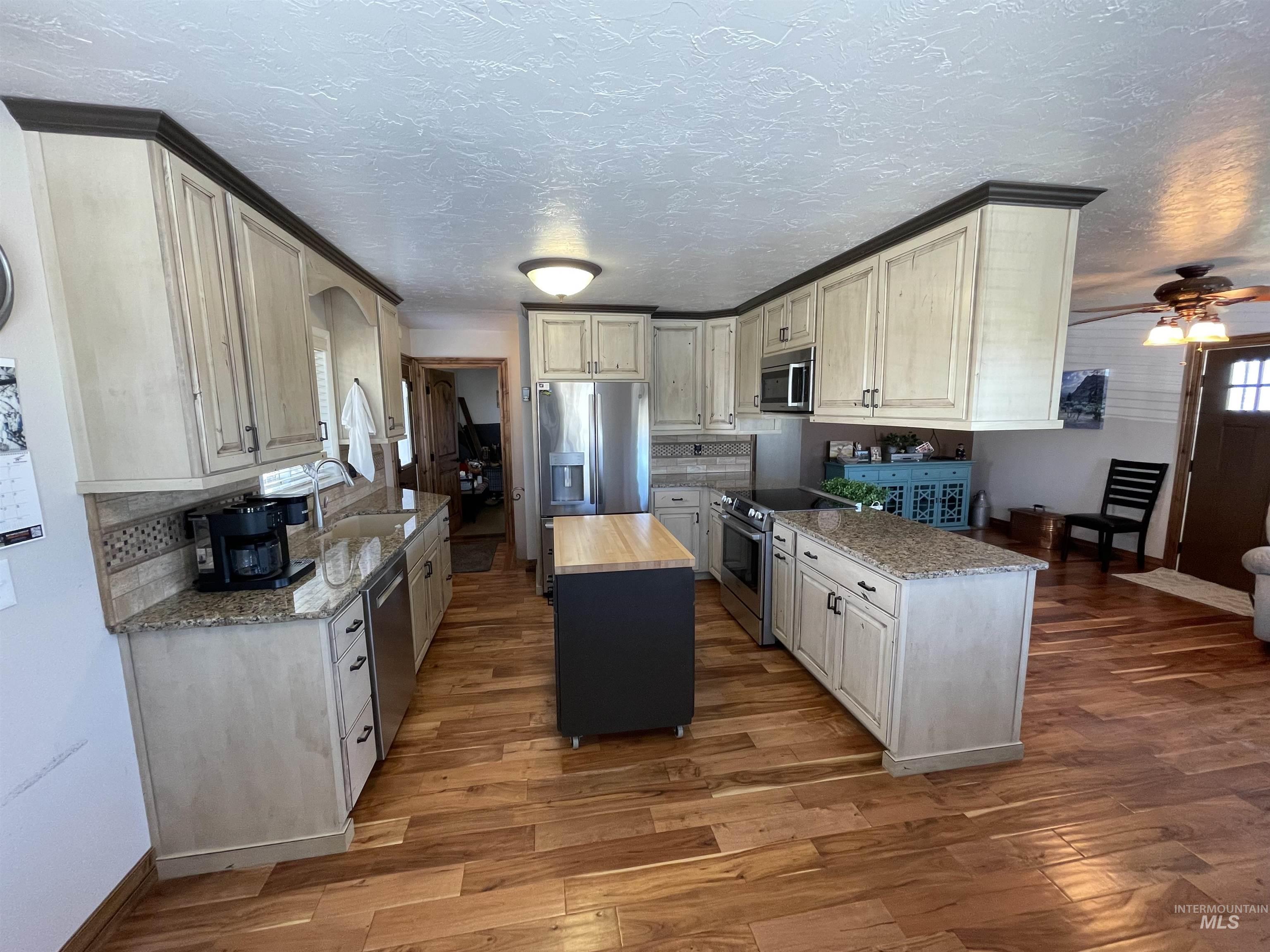 2155 East 1775 South Gooding, ID 83330 - Photo 3 of 18 Kitchen featuring dark stone counters, stainless steel appliances, light wood-type flooring, ceiling fan, and a textured ceiling