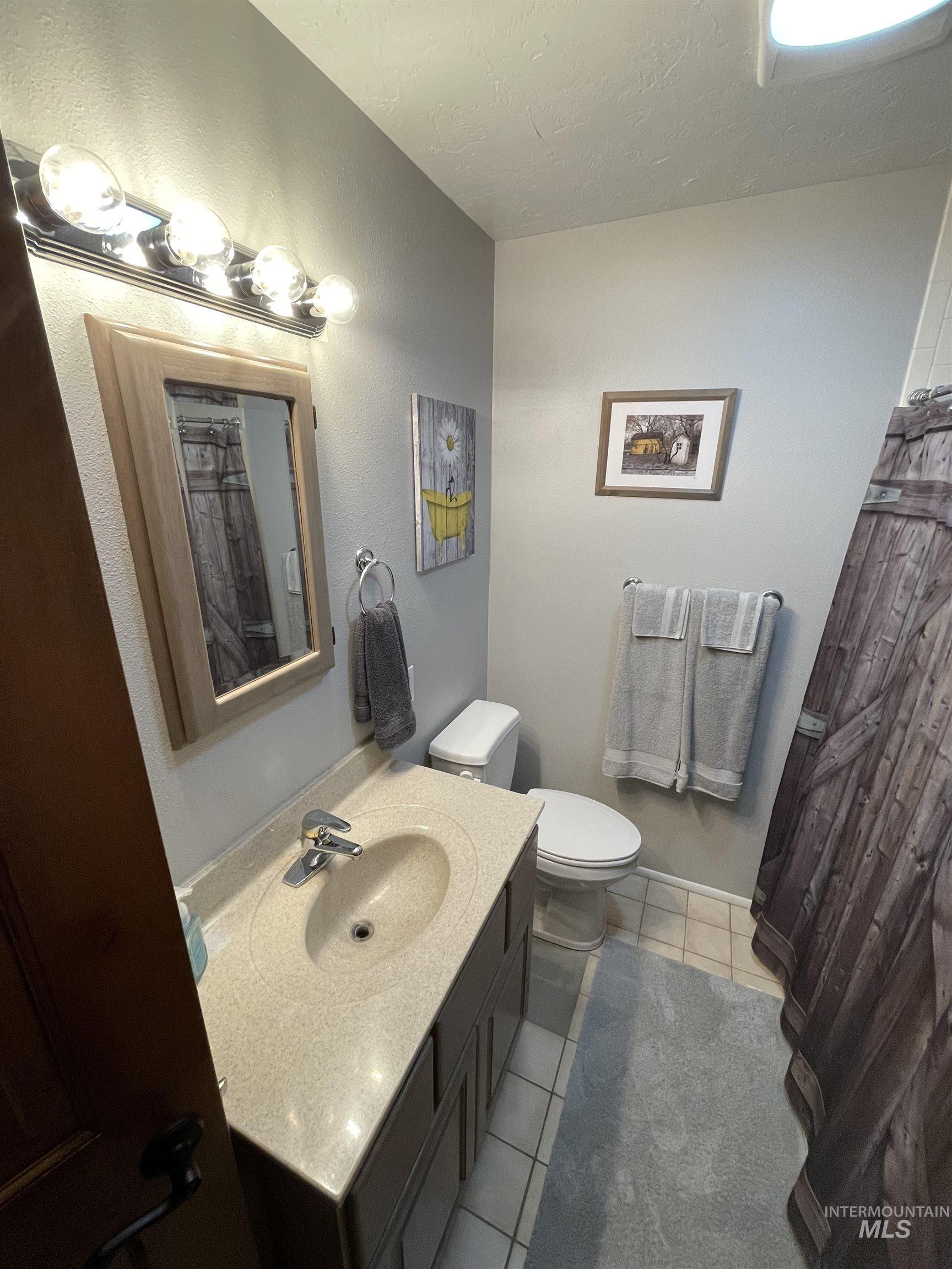 2155 East 1775 South Gooding, ID 83330 - Photo 6 of 18 Full bath with vanity, light tile patterned floors, a textured ceiling, a shower with curtain, and a textured wall