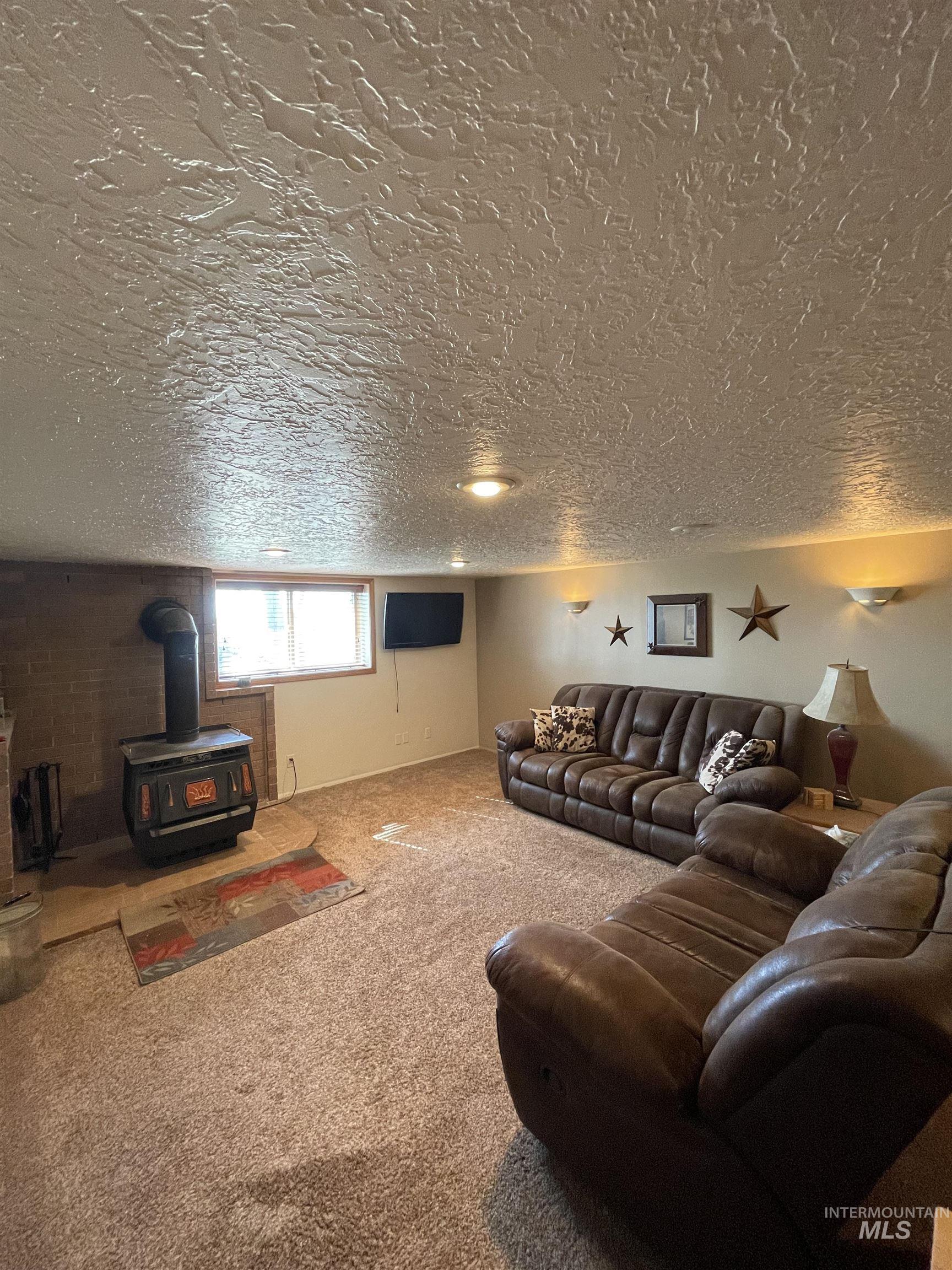 2155 East 1775 South Gooding, ID 83330 - Photo 9 of 18 Carpeted living area featuring a wood stove and a textured ceiling